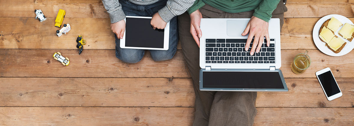 Enfant avec un tablet et père avec ordinateur