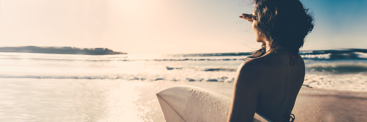 Ein Mädchen mit einem Surfboard am Strand