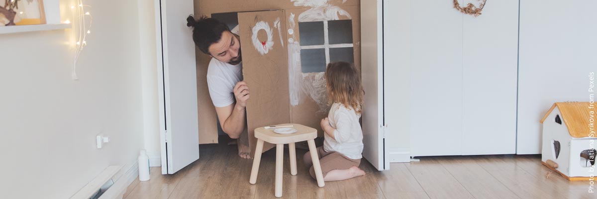 Garçon au pair joue avec un enfant dans une maison en carton