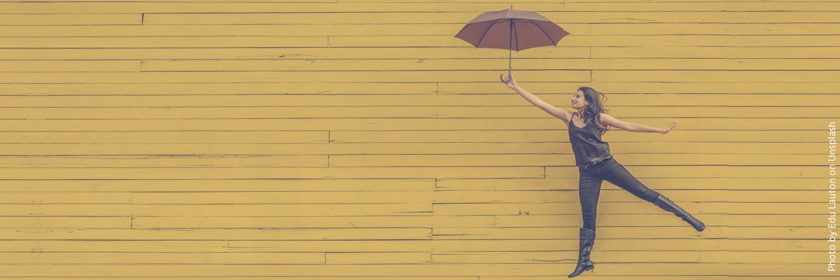 Jonge vrouw met paraplu tegen een gele achtergrond