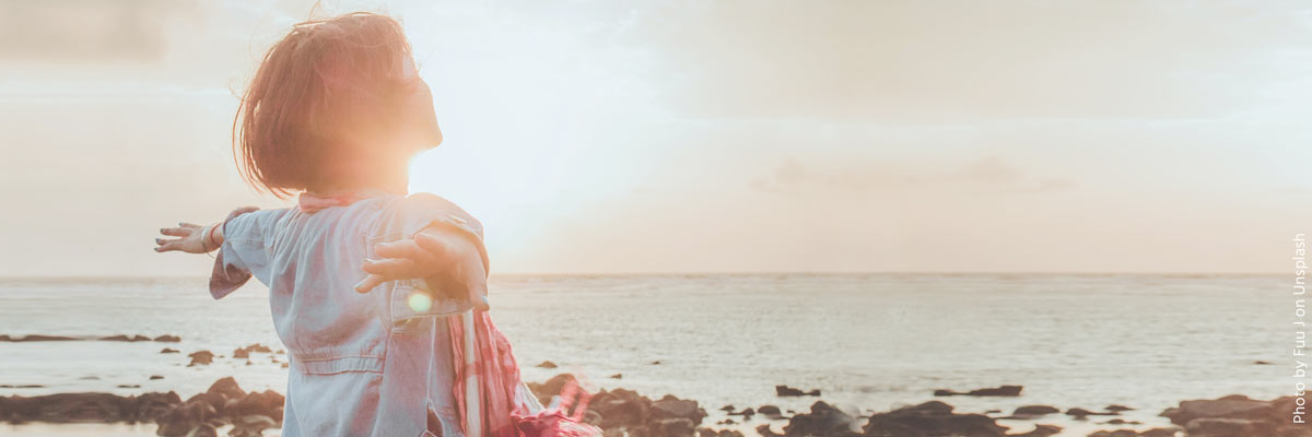 Woman with open Arms in front of the Ocean