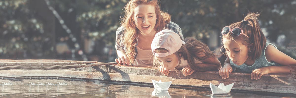 Au-pair with hostkids playing with paperboats