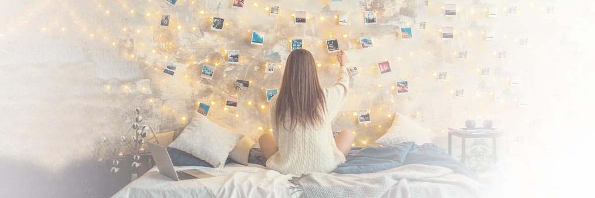 Meisje zit op haar bed in haar kamer en kijkt naar foto's