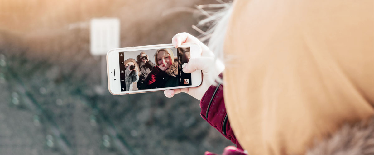 Junge Frau macht Selfie Aufnahmen mit einem Smartphone