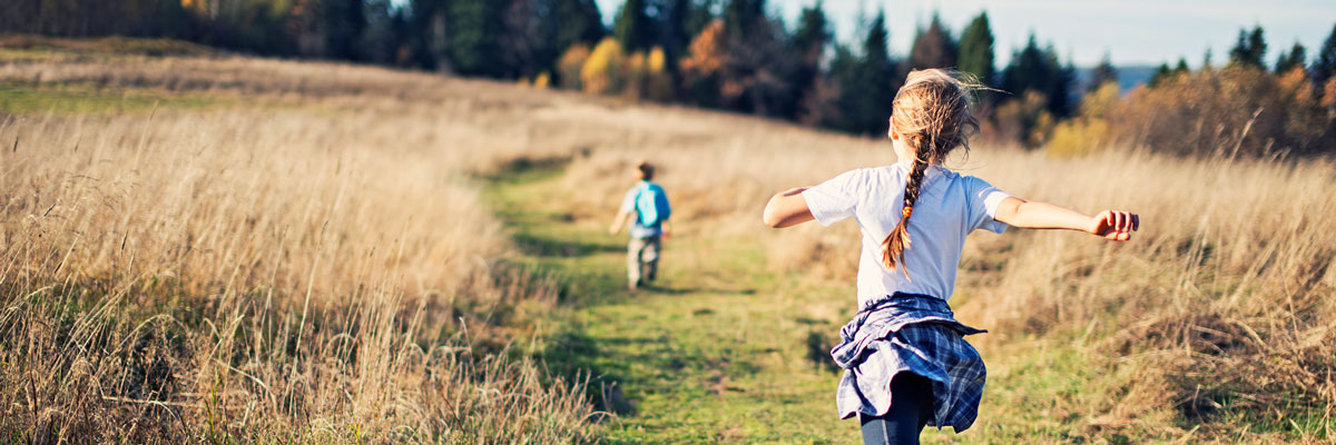 Young children running across a meadow