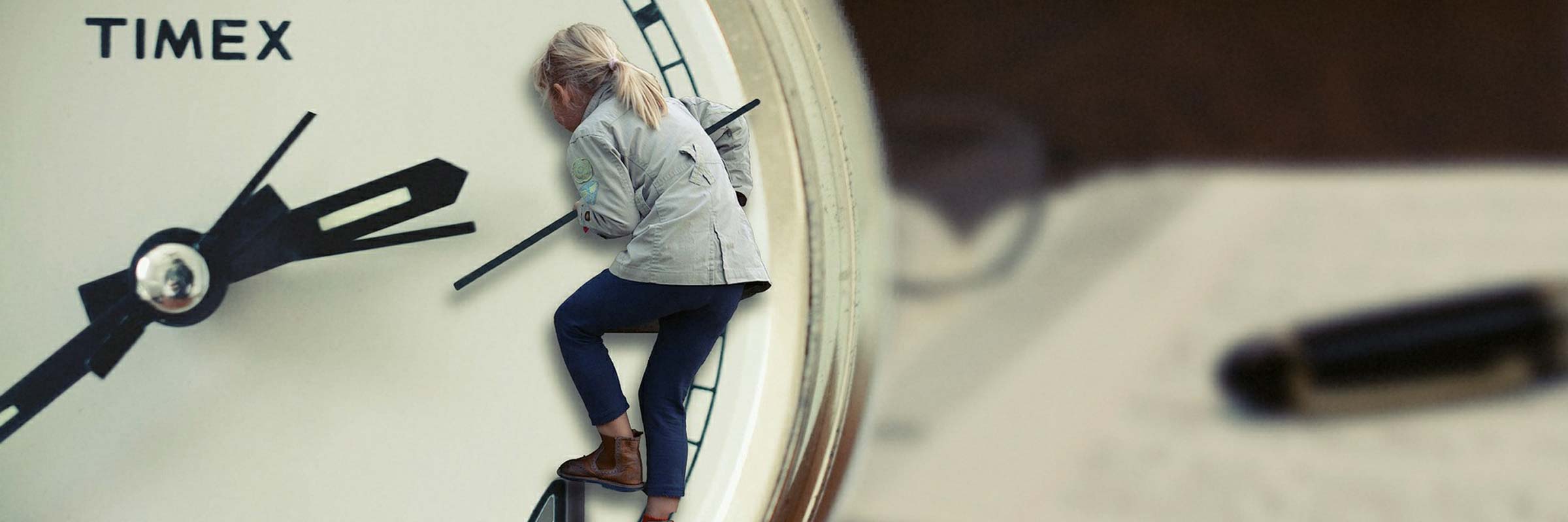 una bambina bionda si arrampica sulle lancette di un orologio