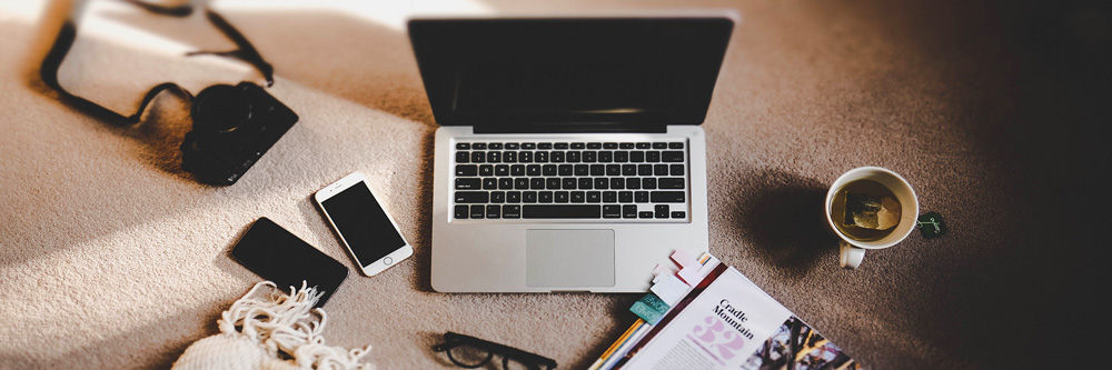 Laptop, camera, cellphone and cup of tea