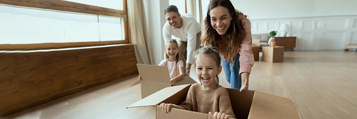 Parents play with cardboard moving boxes with their kids