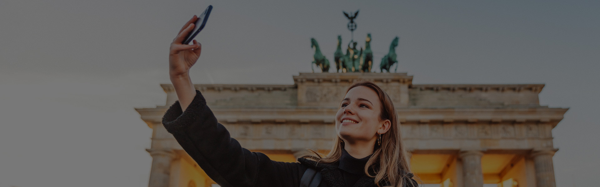 Au pair con smartphone en la Puerta de Brandenburgo en Berlín