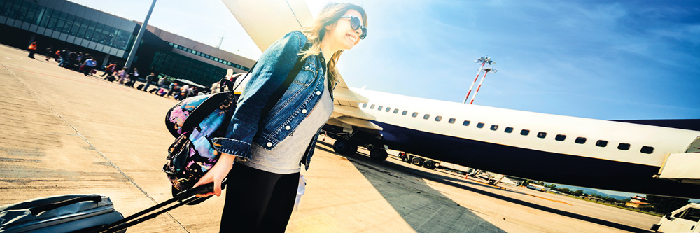 Chica joven con el cielo azul de fondo y un avión pasando