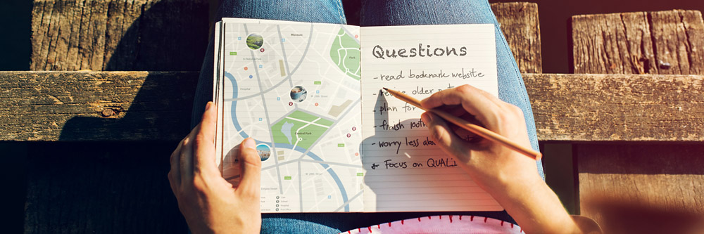 Frau mit beiden Händen auf einer Landkarte und notiert Fragen