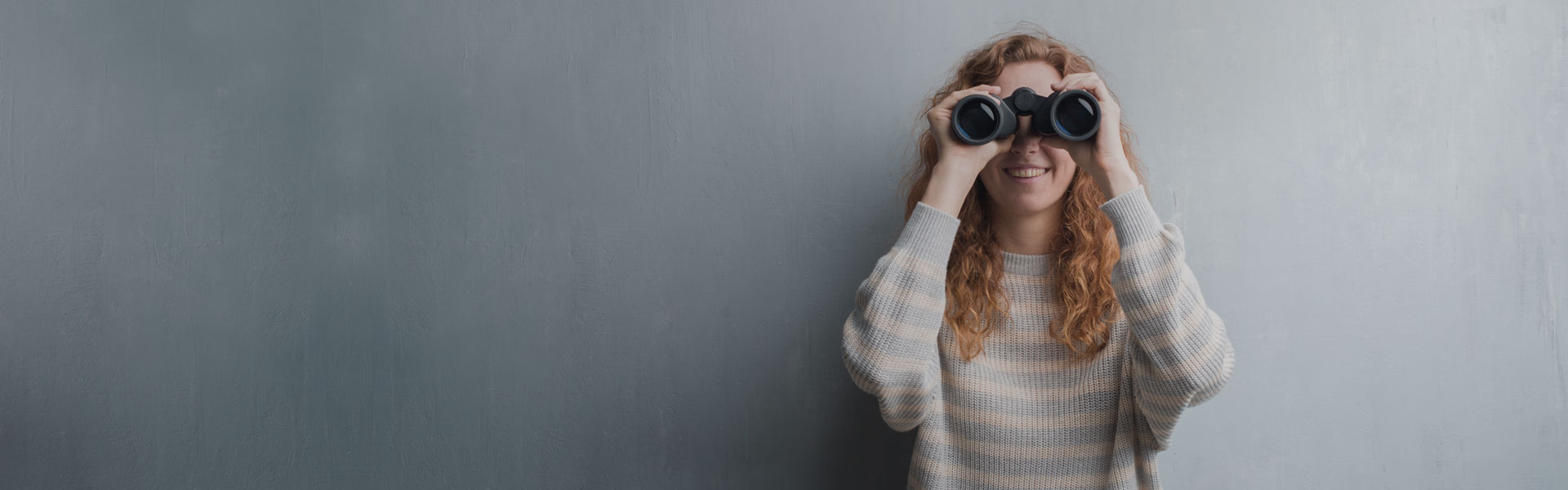 Junge Frau sieht durch ein Fernglas