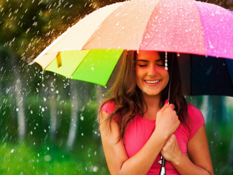 Chica joven con un paraguas bajo la lluvia