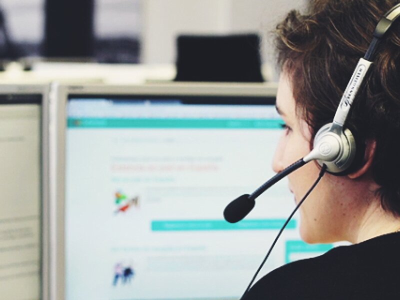 Woman with a headset sits at a computer and supports users of AuPairWorld