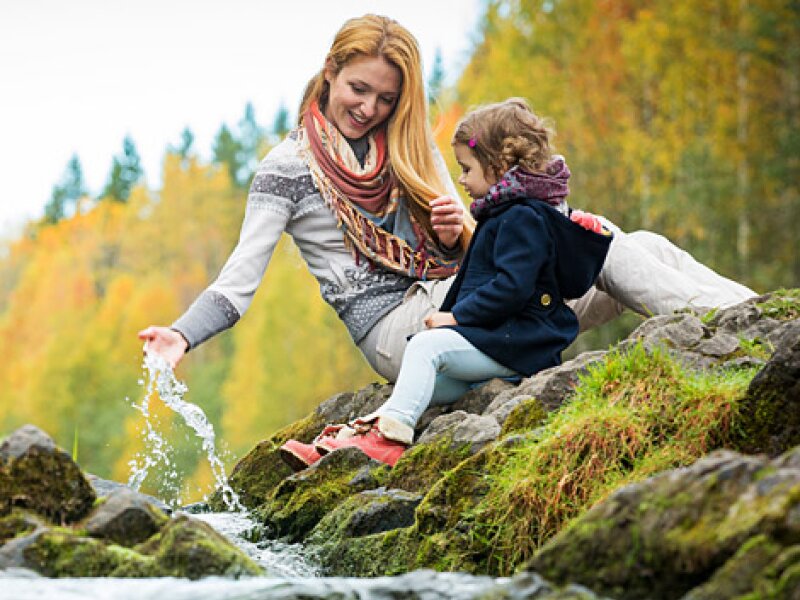 Una giovane donna e un bambino giocano nei pressi di un ruscello