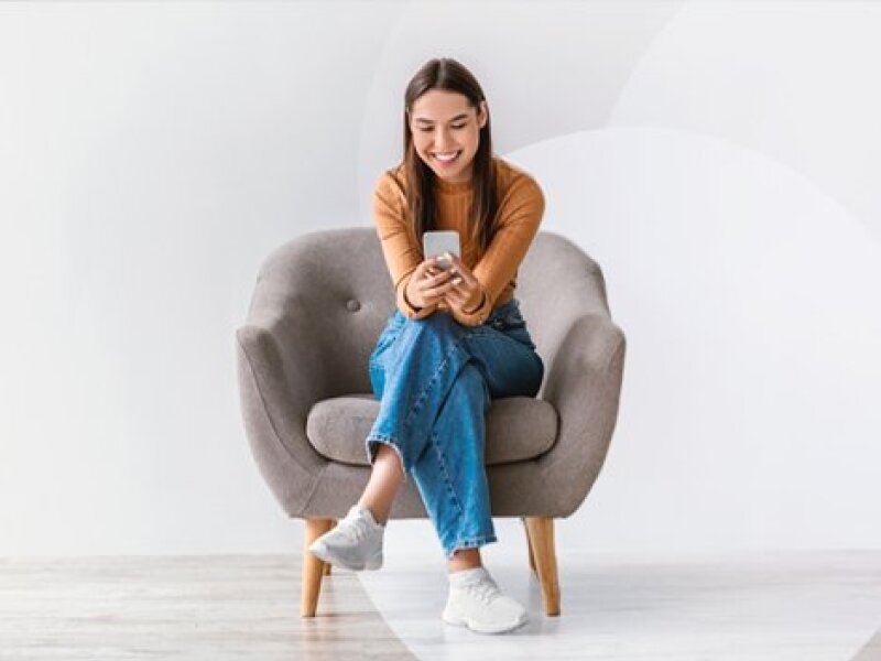 Chica joven con teléfono móvil en un sillón