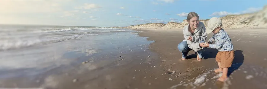 Woman and child playing on a sunny beach.