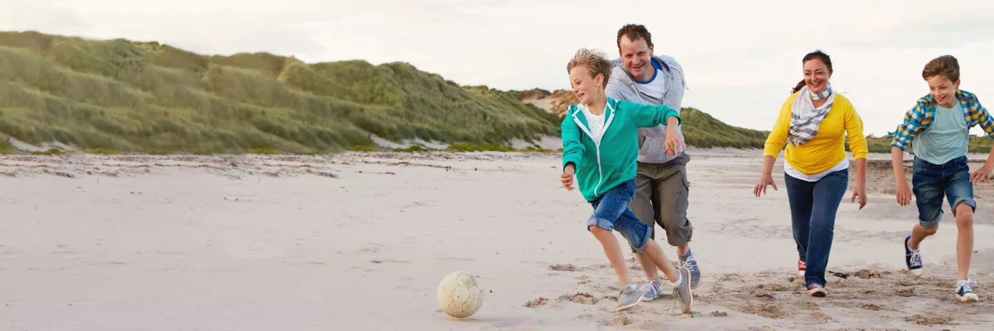 Una famiglia gioca a calcio sulla spiaggia