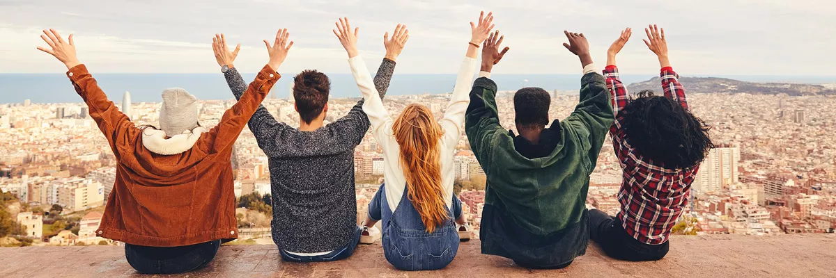 Five people sit in a row on a hill with a view of a city