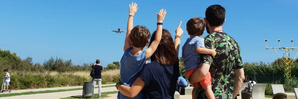 Eine Familie winkt einem Flugzeug zu