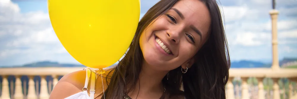 Lächelnde Person mit einem gelben Ballon