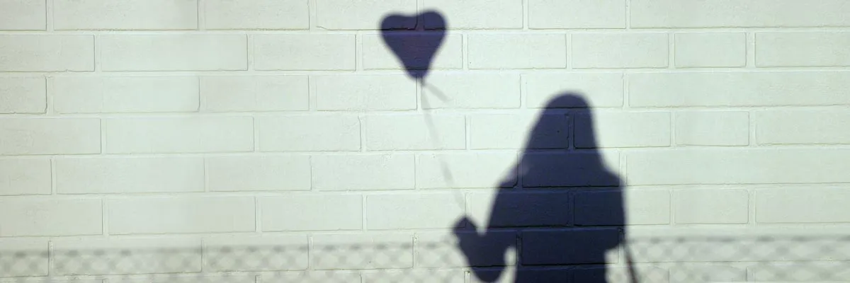 Shadow of a figure holding a heart balloon
