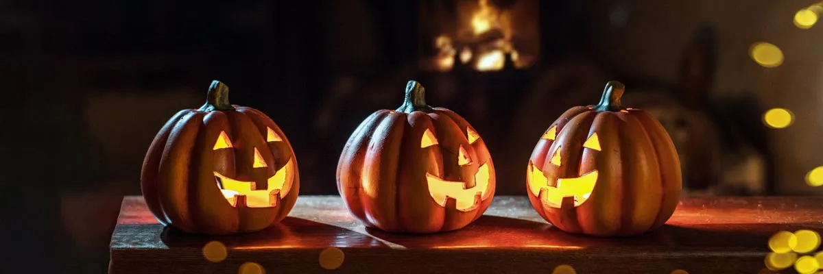 Tres calabazas talladas con velas encendidas en el interior
