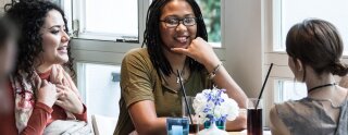 Trois filles parlent et boivent à table