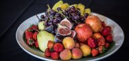 Piatto con fragole, prugne, mele, pere, fichi, uva americana e banane