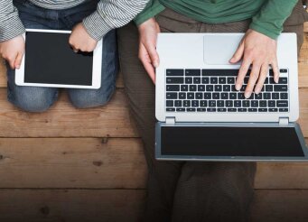 Un enfant avec une tablette et un père avec un ordinateur