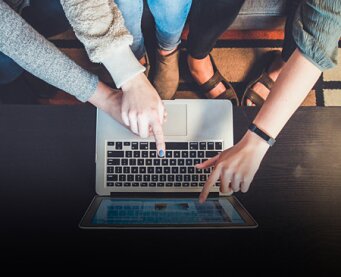 Several people look at a laptop together