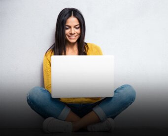 Vrouw zit in kleemakerzit met een laptop op haar been