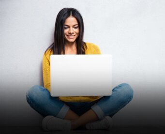 Young woman sitting cross-legged with a laptop on her lap