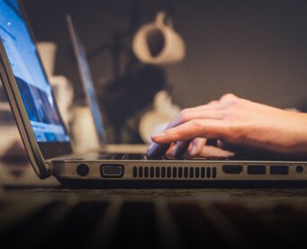 Hands typing on a laptop