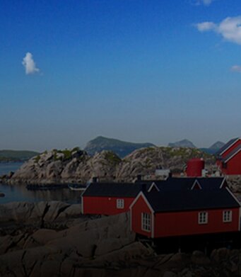 Kleines norwegisches Dorf am Wasser mit Bergen im Hintergrund