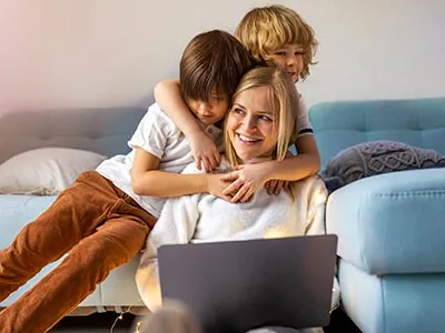 a woman and two kids with a laptop