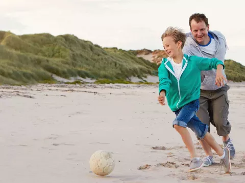 A family plays football on the beach