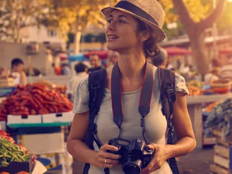 Young traveller in a market with camera in hand