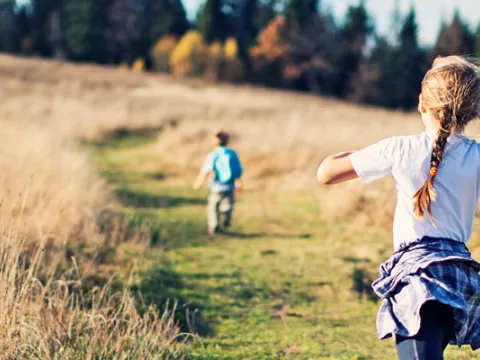 Young children running across a meadow