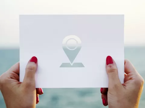 Woman's hands holding card with location icon