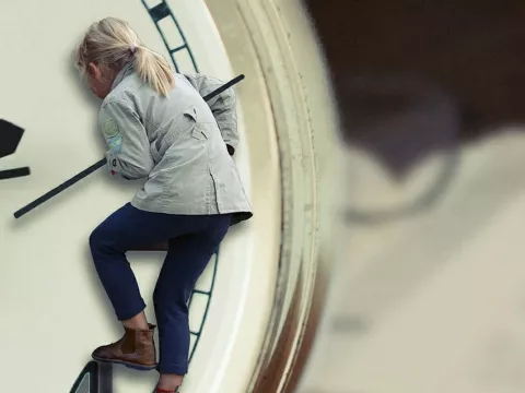 A child climbs on the face of a clock