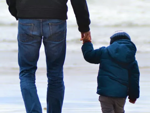 Mann and Child hand in hand on the beach