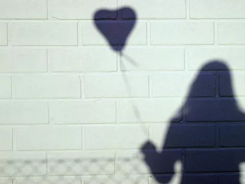 Shadow of a figure holding a heart balloon