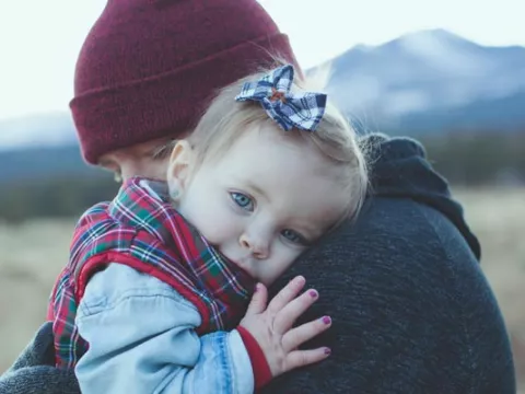 A parent holds their child in their arms