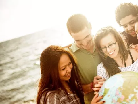 A group of young people point to a water ball globe