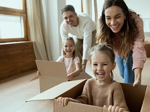 Parents play with cardboard moving boxes with their kids