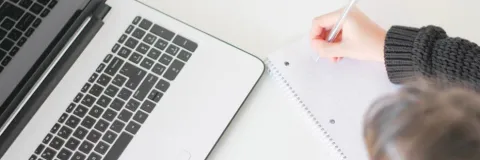 Woman taking notes with her laptop in front of her