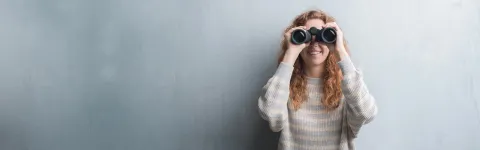 Young woman looks through binoculars