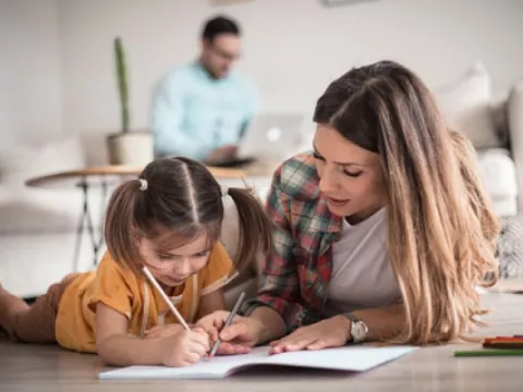 Ein Au-pair hilft einem Kind beim malen
