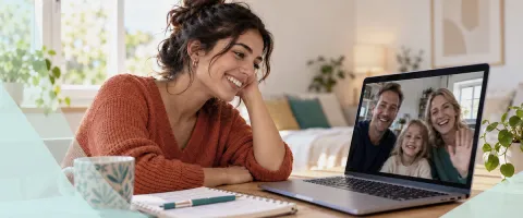 Woman smiling at laptop during a video call with a family.